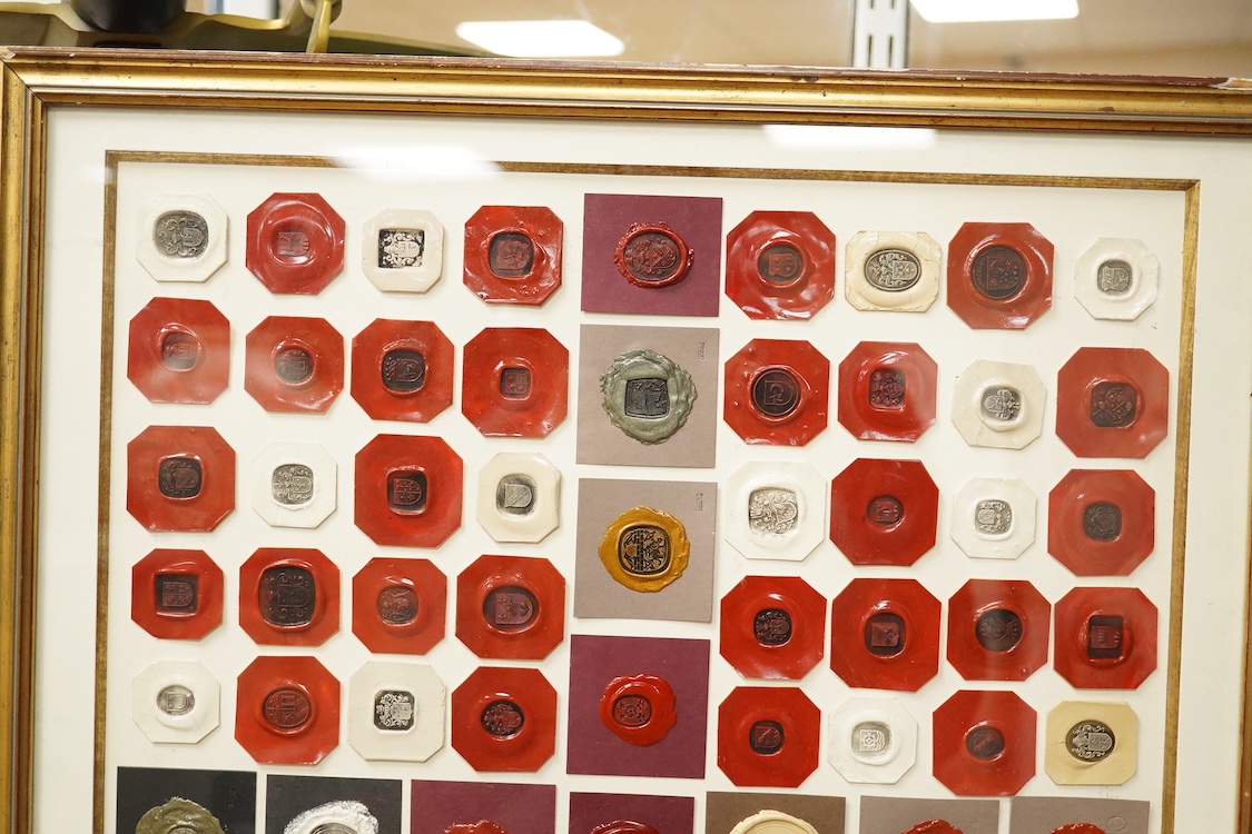 A framed display of red and white wax seals, some stamped Casolo Lausanne, 95 in total, 59cm wide